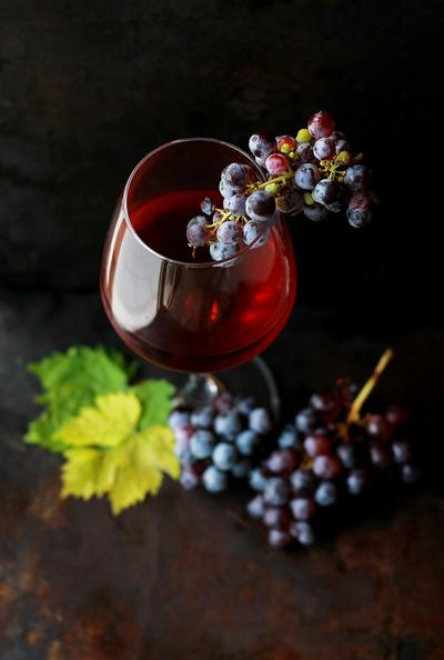 Bicchiere di rosso con uva e una foglia